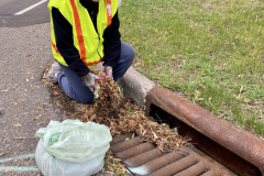 A volunteer cleans a storm drain at our May 2025 Adopt-a-Drain event